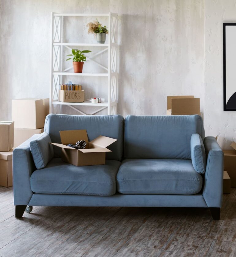 Canapé microfibre bleu dans salon avec cartons de déménagement