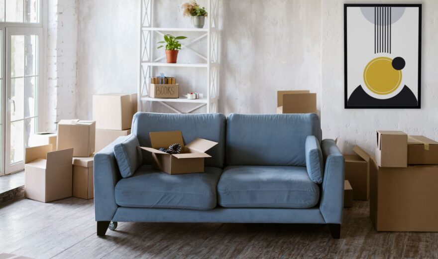 Canapé microfibre bleu dans salon avec cartons de déménagement