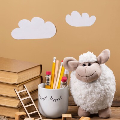 Image enfantine avec un mouton, des livres et des crayons Image enfantine avec un mouton, des livres et des crayons